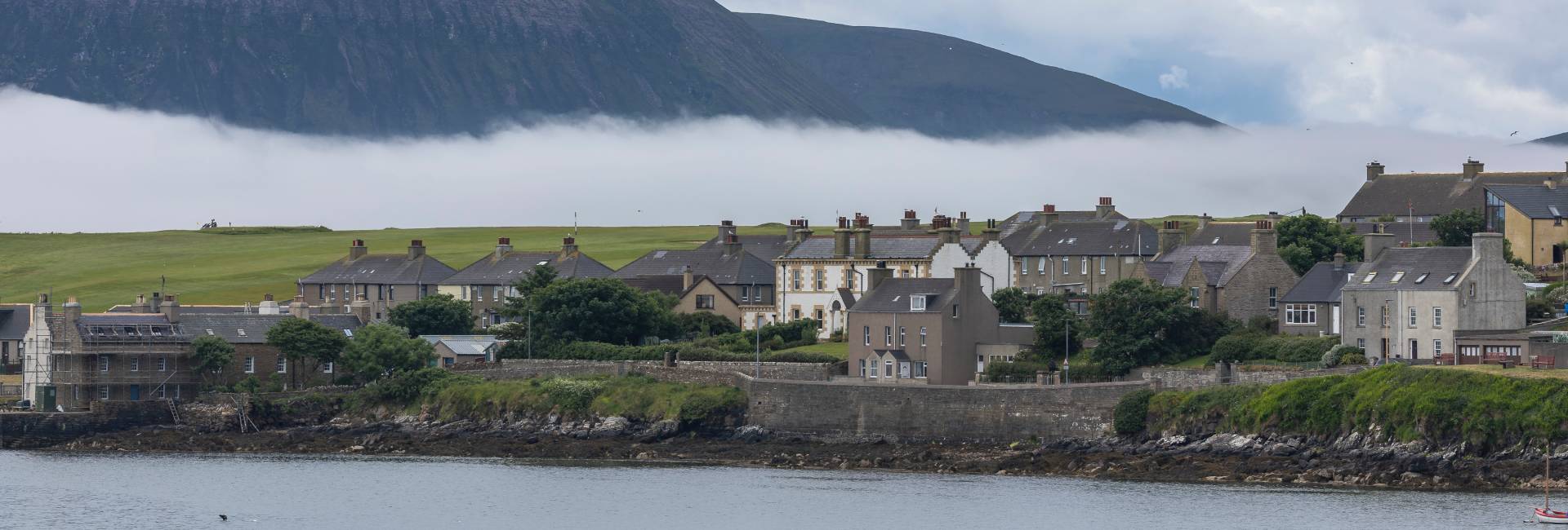 Coastal village, low cloud and hills, Orkney, Scotland, UK, June